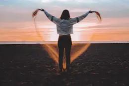 woman forming heart with sand on beach 260x173