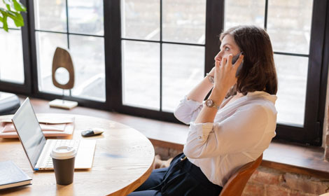 woman speaking on mobile phone in front of laptop