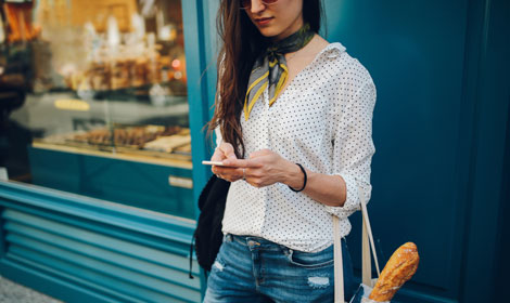 Woman using mobile outside store (470x280px)